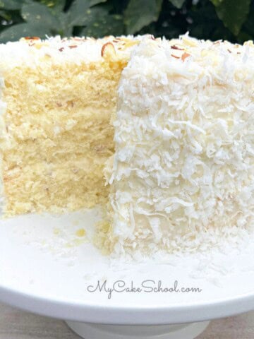 Almond Coconut Cake, sliced, on a cake pedestal.