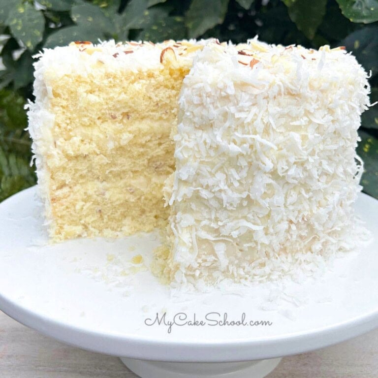 Almond Coconut Cake, sliced, on a cake pedestal.