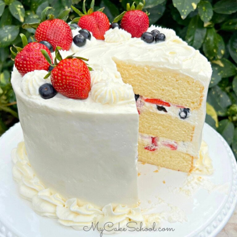 Moist Berry Chantilly Cake, sliced, on a cake pedestal.