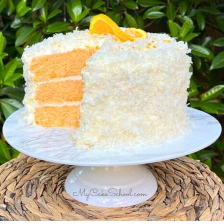 Orange Coconut Cake, sliced, on a cake pedestal.