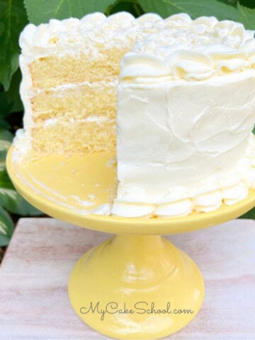 Moist Pineapple Dream Cake, sliced, on a cake pedestal.