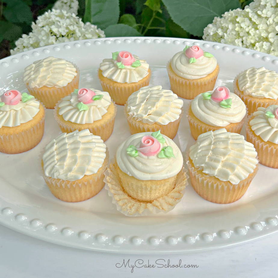 Vanille-Cupcakes mit Buttercreme-Rüschen und Rosen.