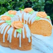 Sliced Orange Bundt Cake with glaze and topped with orange buttercream rosettes.