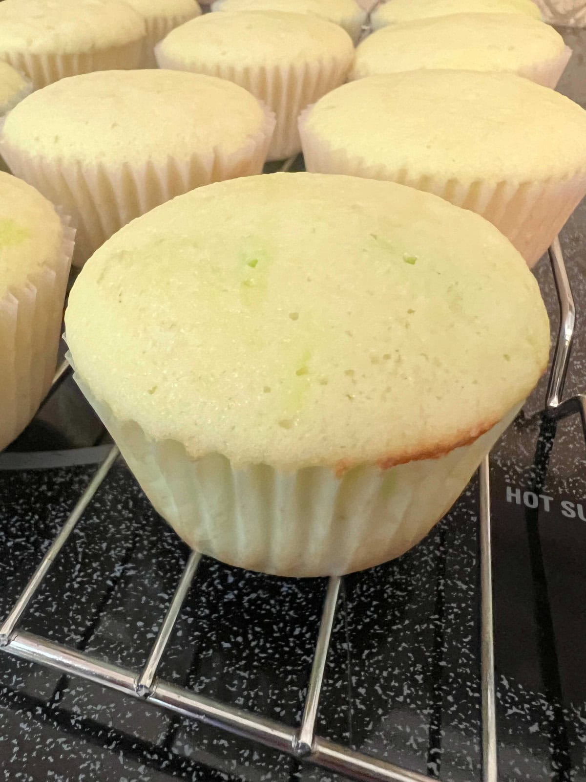 Lime cupcakes cooling on a cooling rack.