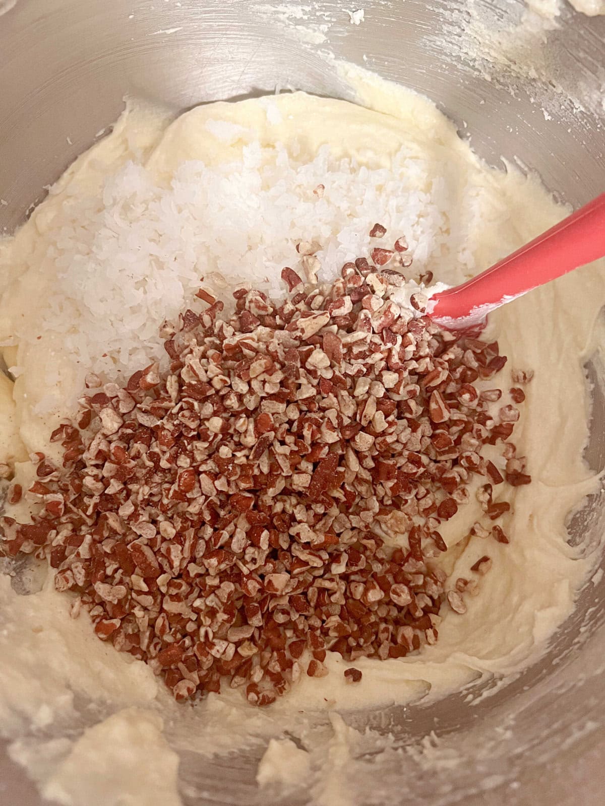 Mixing bowl of cake batter with flaked coconut and pecan pieces (just before incorporating.)