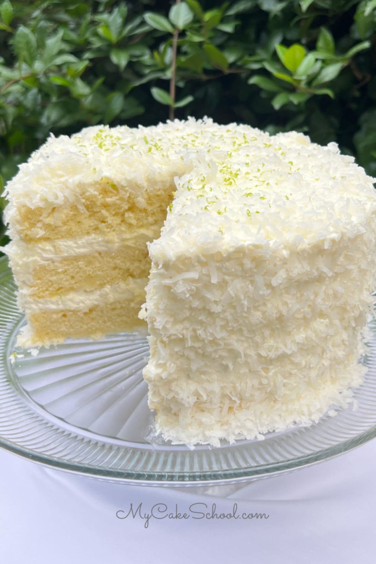 Key lime coconut cake, sliced, on a pedestal.