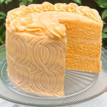 Orange Velvet Cake, sliced, on a cake pedestal.