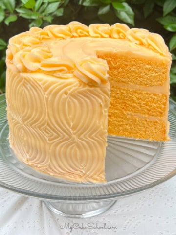 Orange Velvet Cake, sliced, on a cake pedestal.