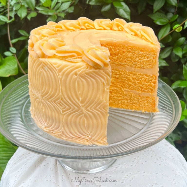 Orange Velvet Cake, sliced, on a cake pedestal.