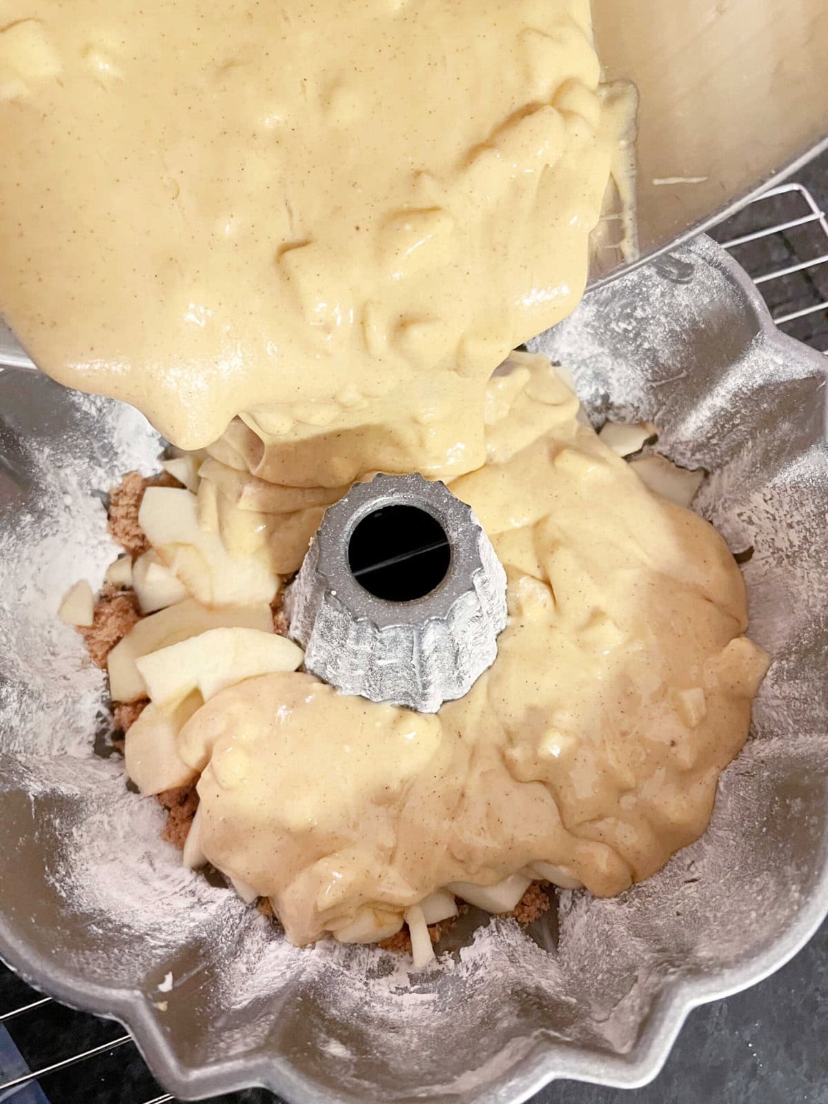 Pouring batter into the bundt pan , over the brown sugar, butter, and apple slices, for apple upside down cake.