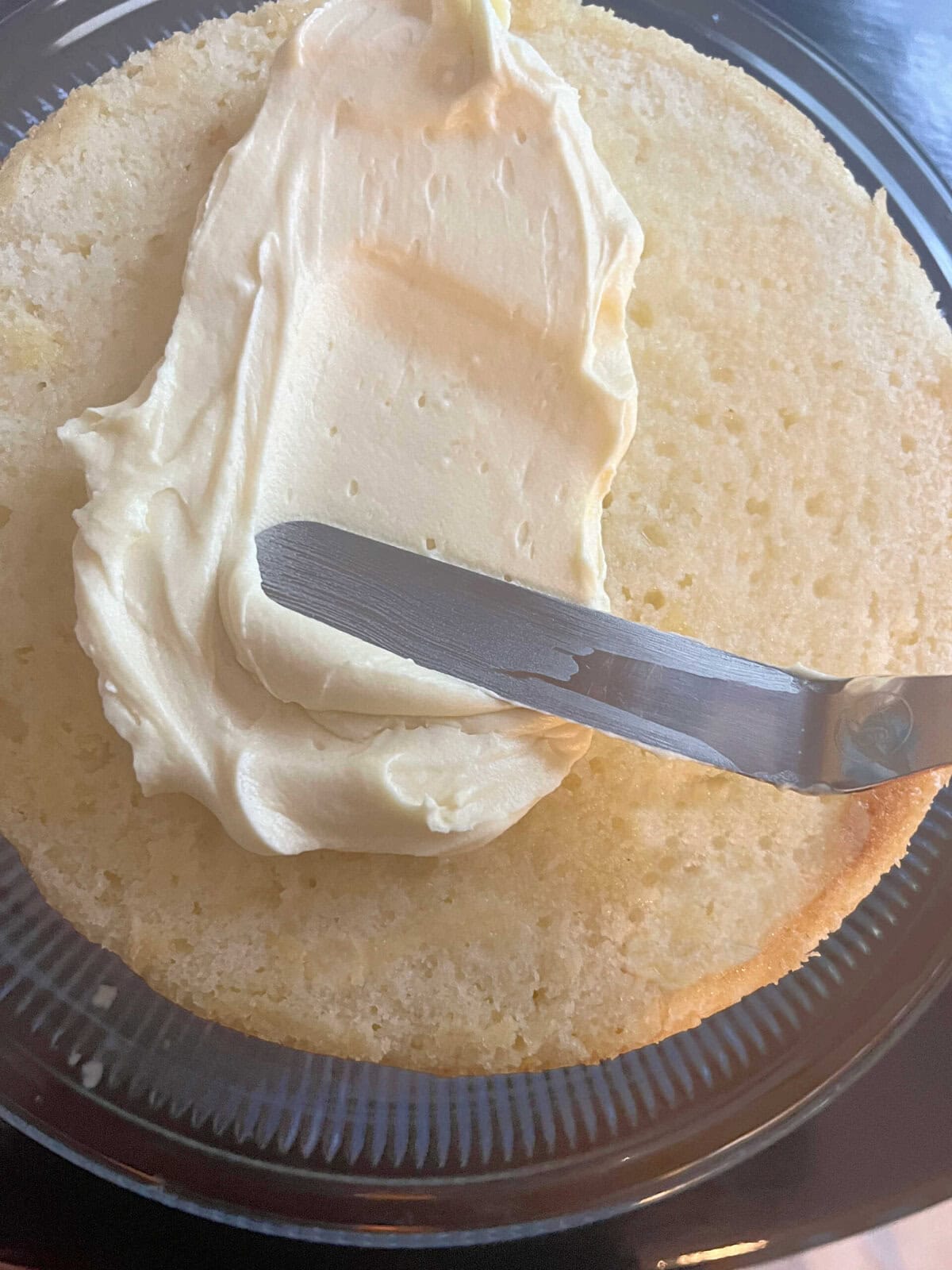 Applying lemon cream cheese frosting to the cake layer.