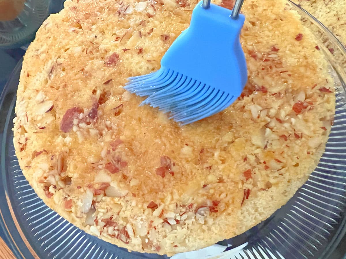 Glazing the maple almond cake layer.