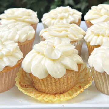 Spice cupcakes with orange cream cheese frosting on a platter.