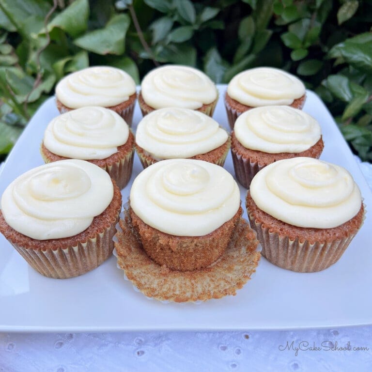 Gingerbread Cupcakes on a cake platter, frosted with cream cheese frosting.