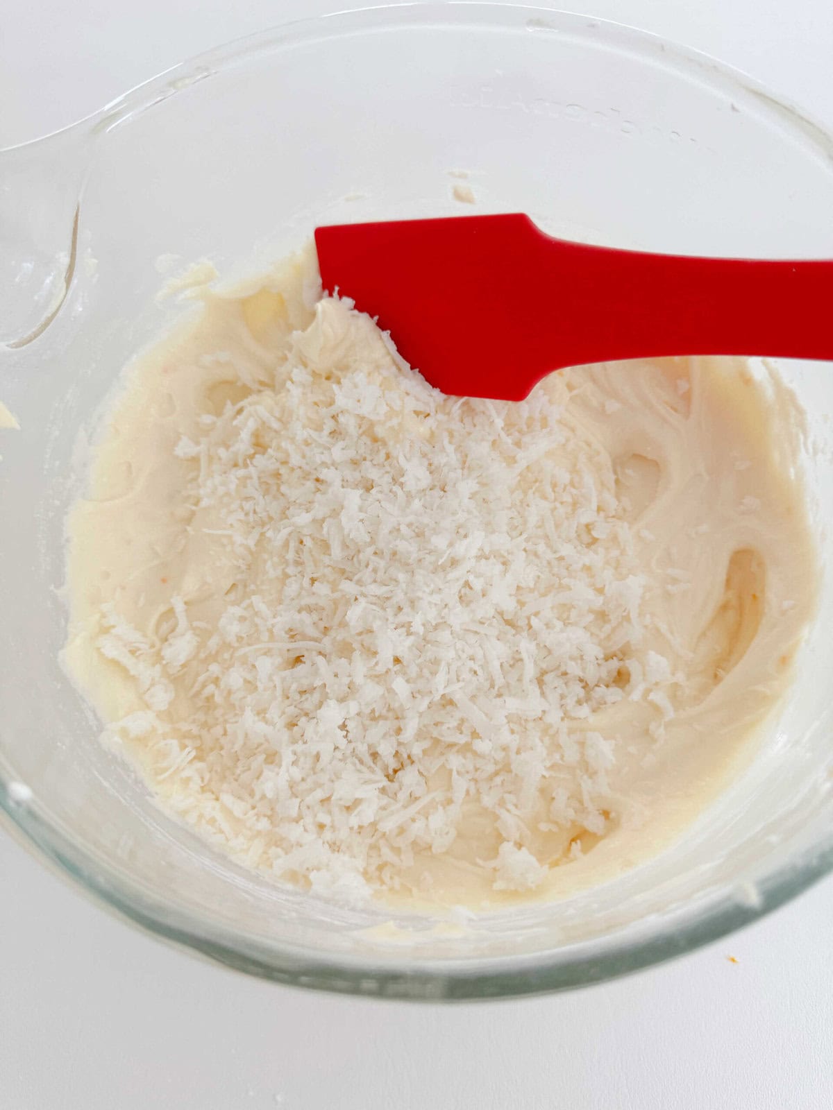 Folding sweetened flaked coconut into the cake batter.