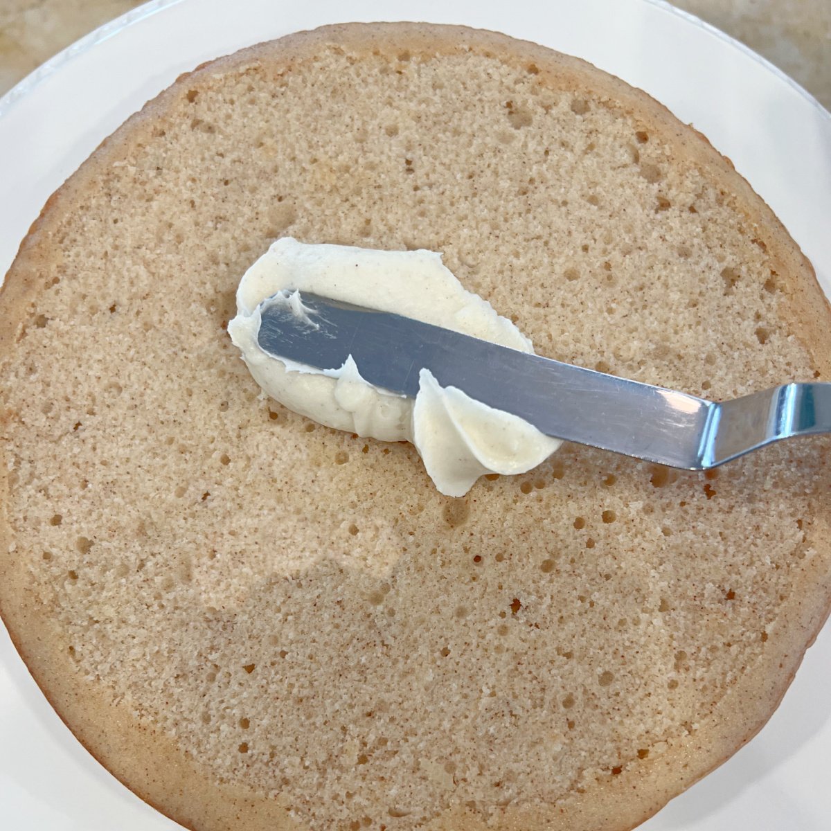 Applying frosting to cake layer.