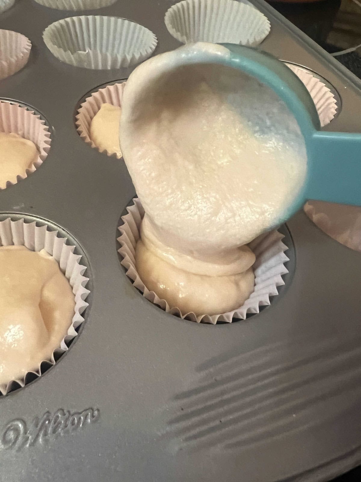 Filling the cupcake liners with pink champagne cake batter.