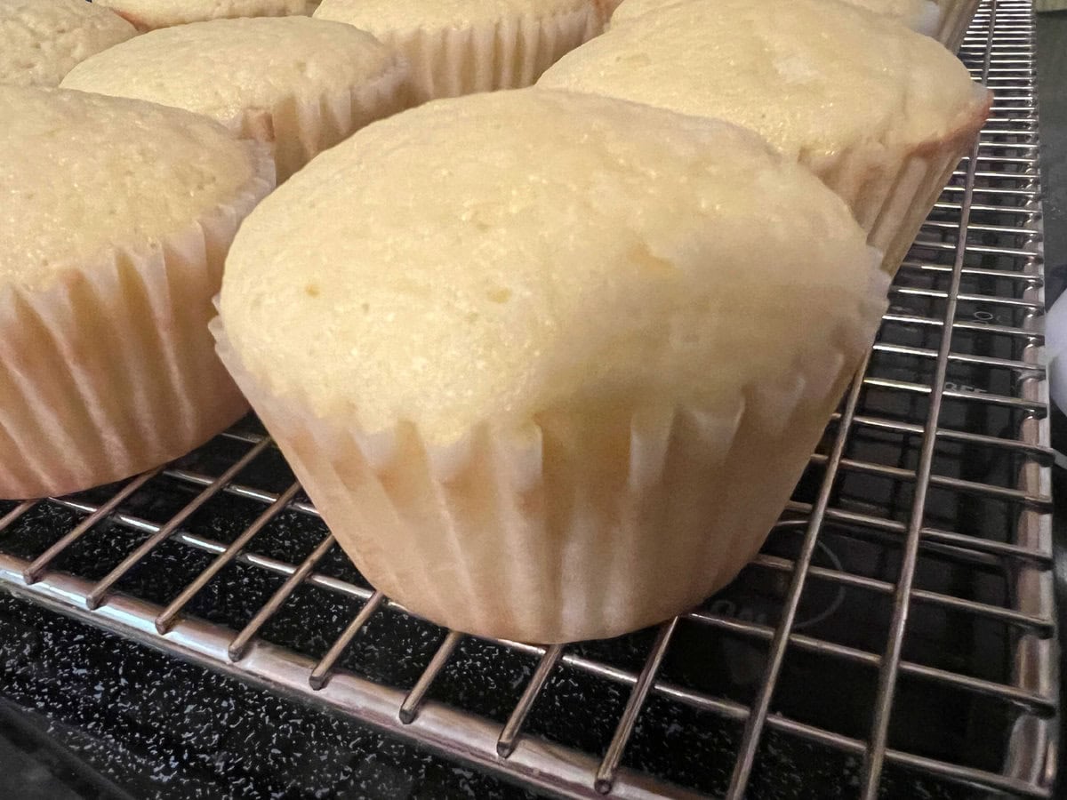 Freshly baked lemon sour cream cupcakes, cooling on a wire rack.