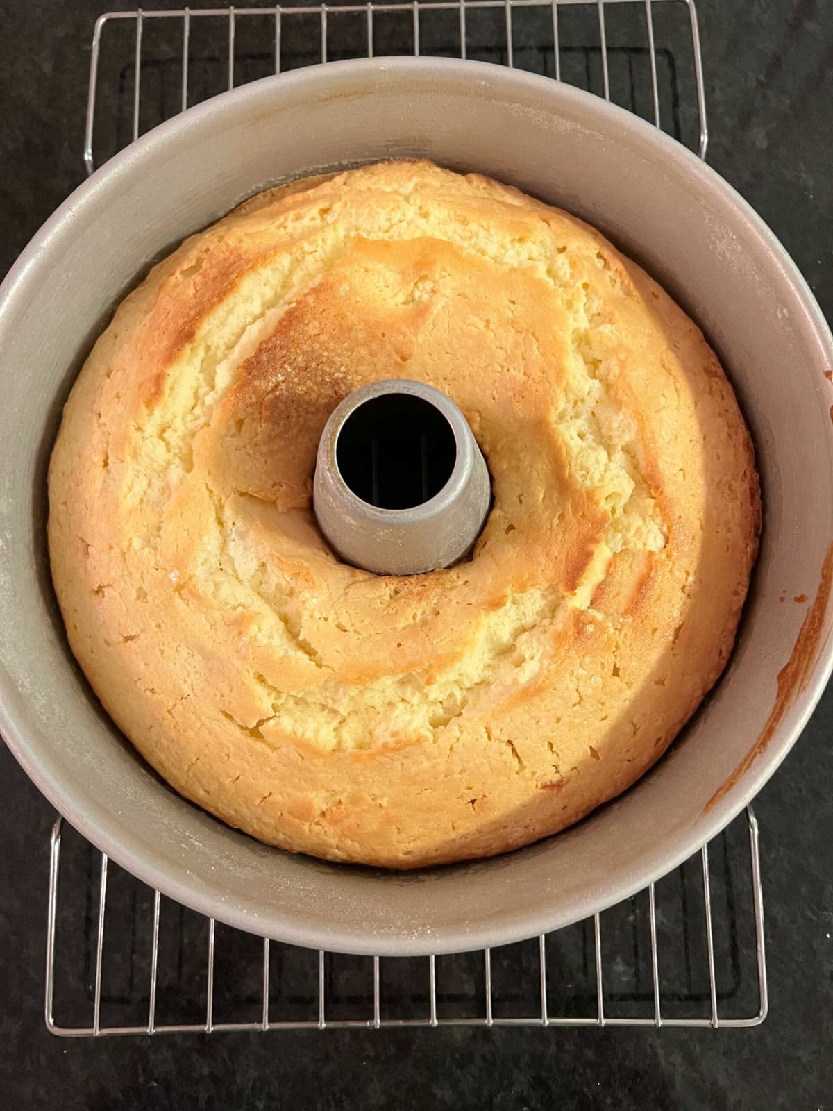 Freshly baked cake, still in pan, cooling on a wire rack.