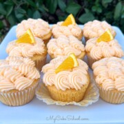 Orange Cupcakes with Cream Cheese Frosting on a cake platter.