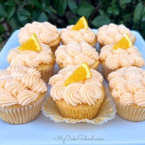 Orange Cupcakes with Cream Cheese Frosting on a cake platter.