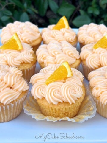 Orange Cupcakes with Cream Cheese Frosting on a cake platter.