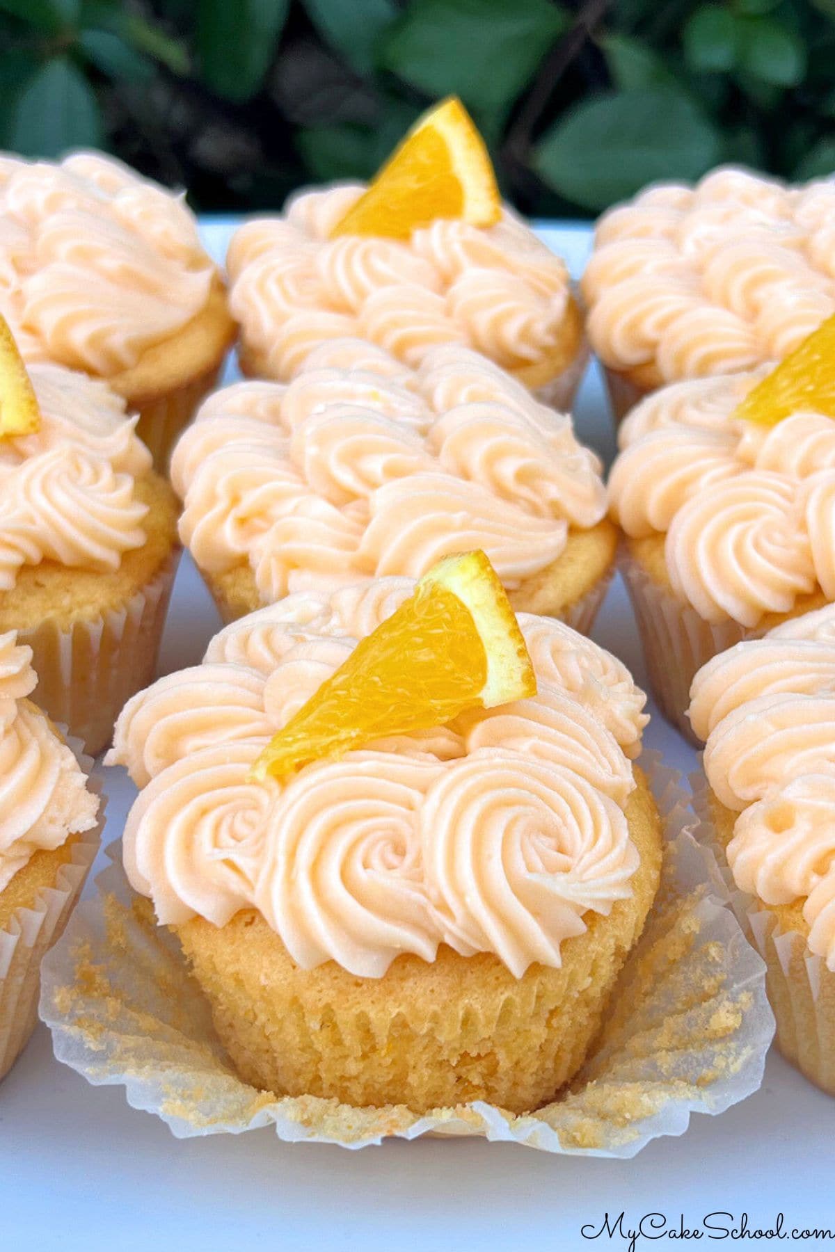 Orange cupcakes on a cake platter.