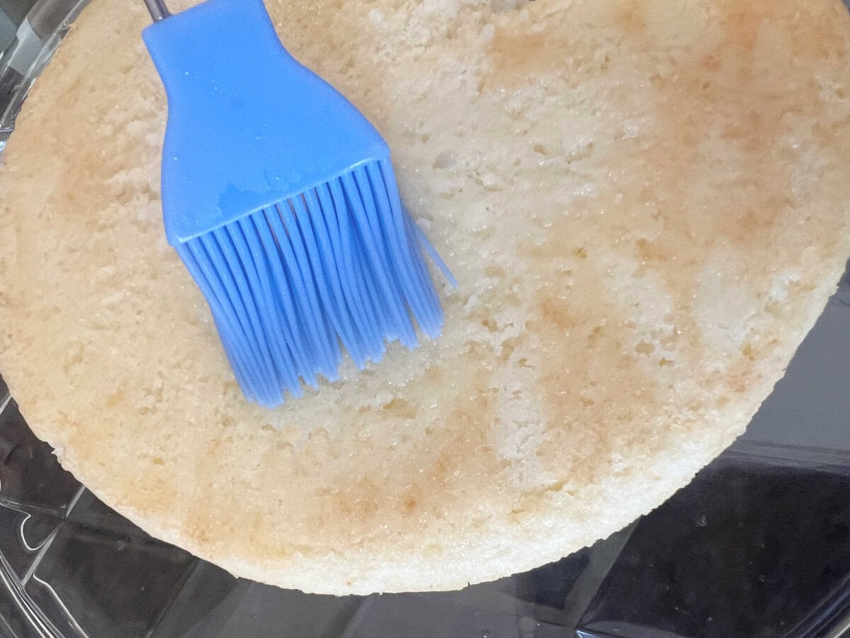 Brushing Champagne Syrup over a cake layer.