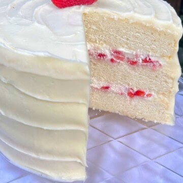 Strawberries and Cream Cake, sliced, on a cake pedestal.