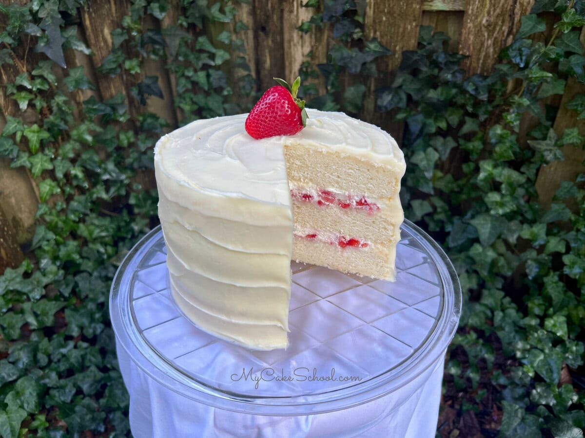 Strawberries and Cream Cake, sliced, on a pedestal.