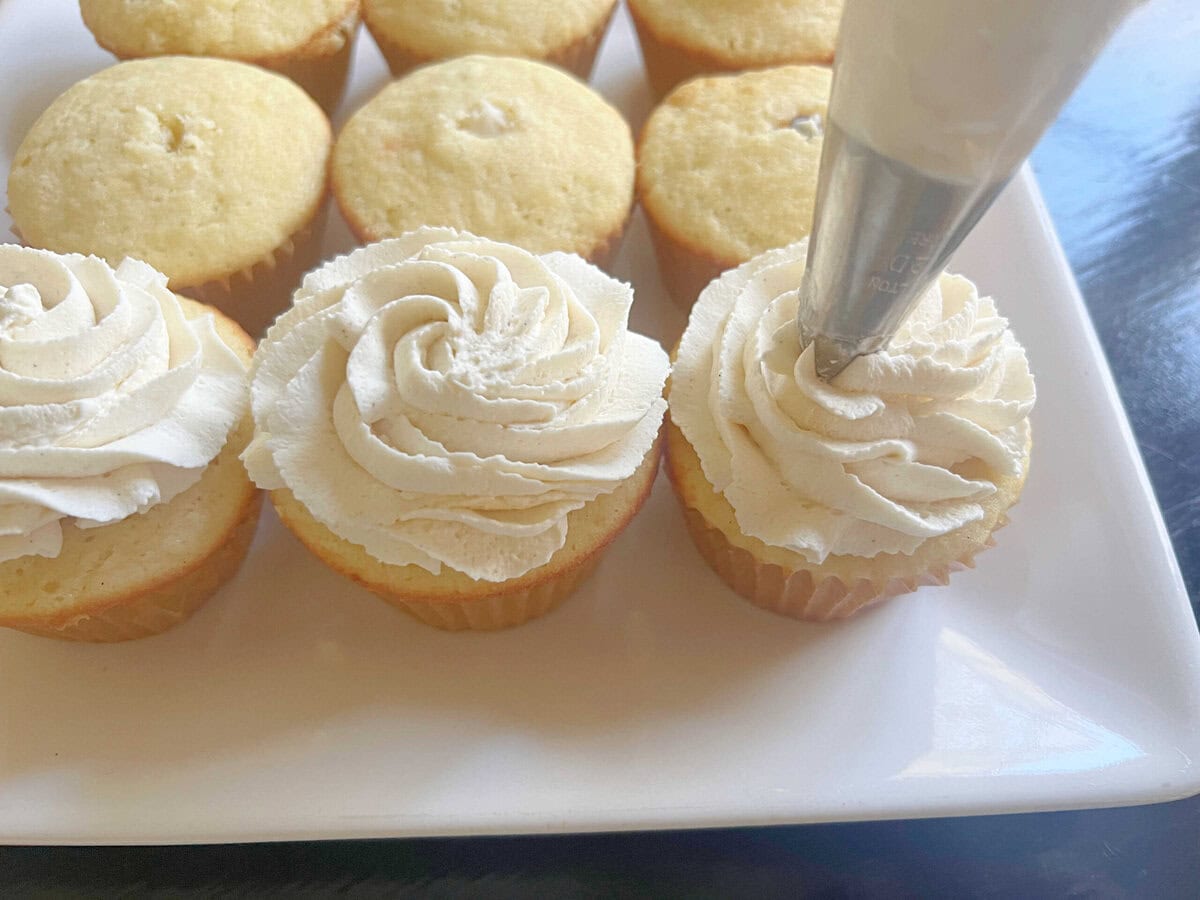 Piping frosting onto the cannoli cupcakes.